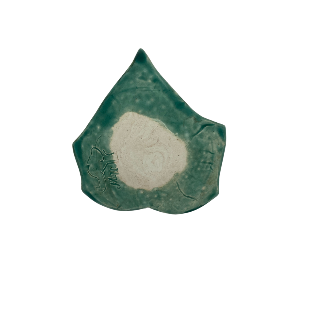 Bottom view of A hand-crafted green leaf-shaped trinket dish on a white background.