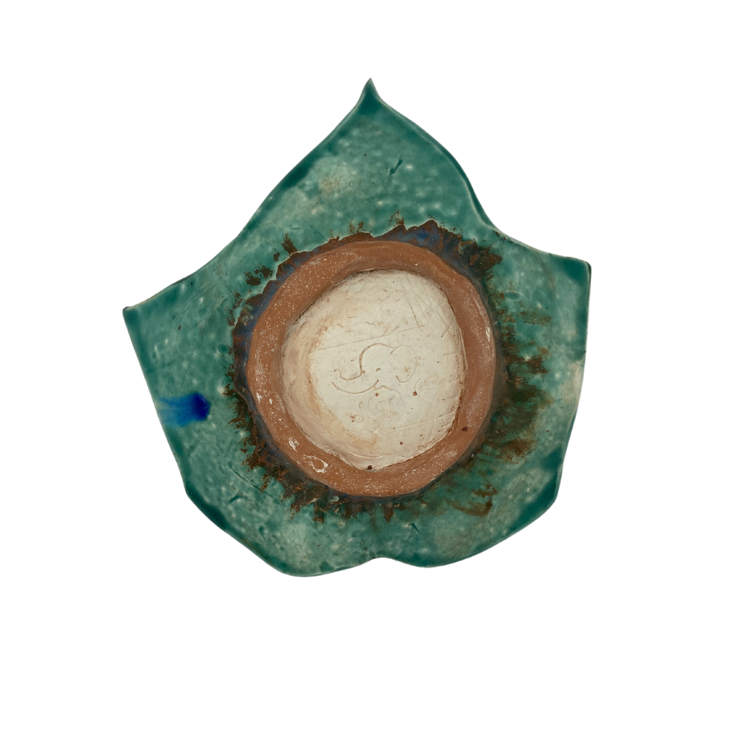 bottom view of A hand-crafted green leaf-shaped trinket dish on a white background.