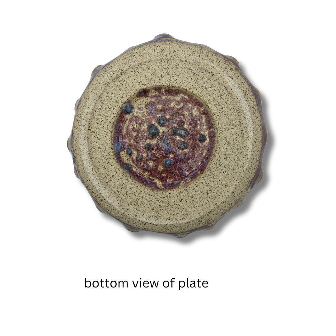 bottom view of A purple and gold ceramic chip and dip plate with a floral pattern, on a white backgroud