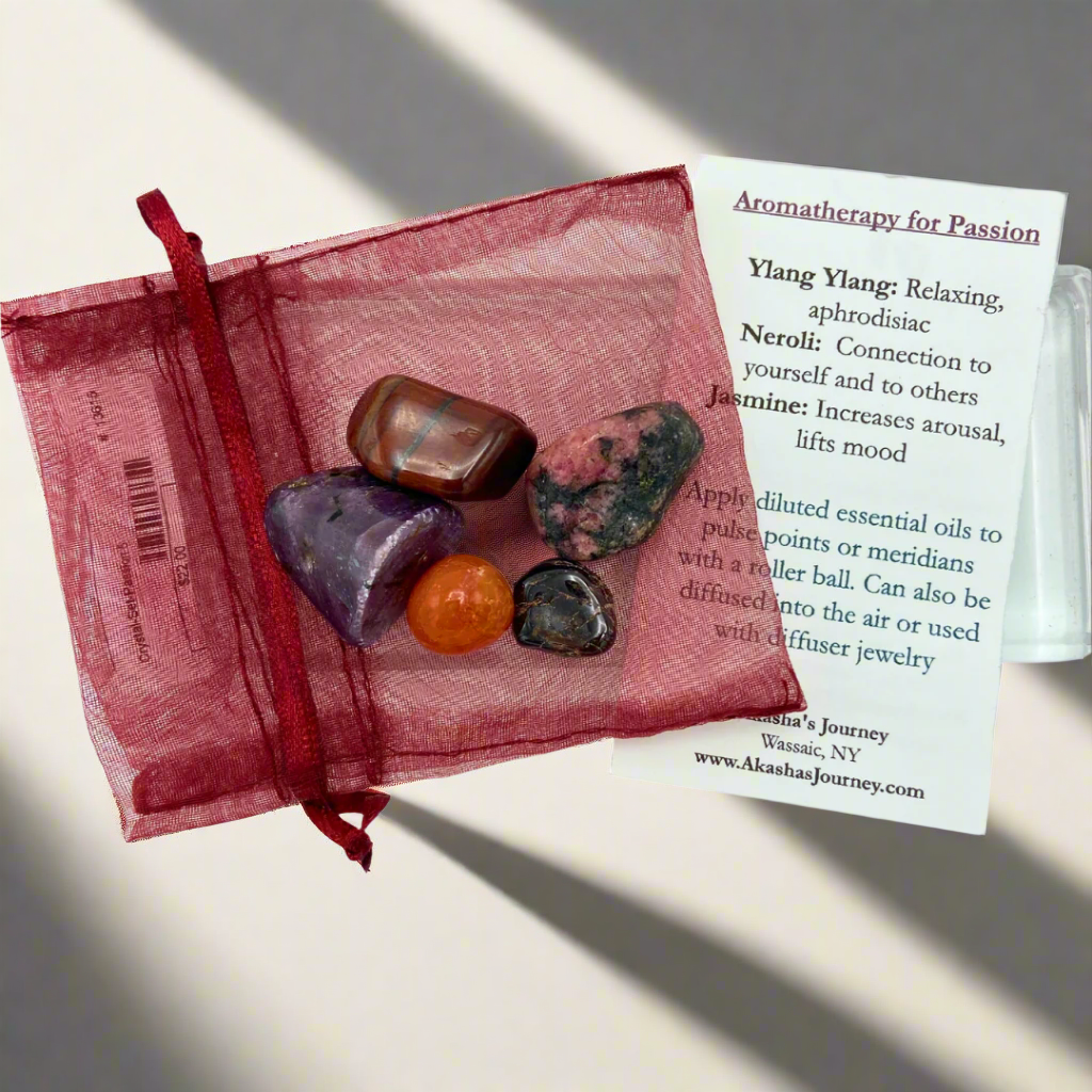 A red organza bag containing various polished gemstones, tied with a red ribbon, with a card labeled 'Passion Mojo Crystal Pack'.