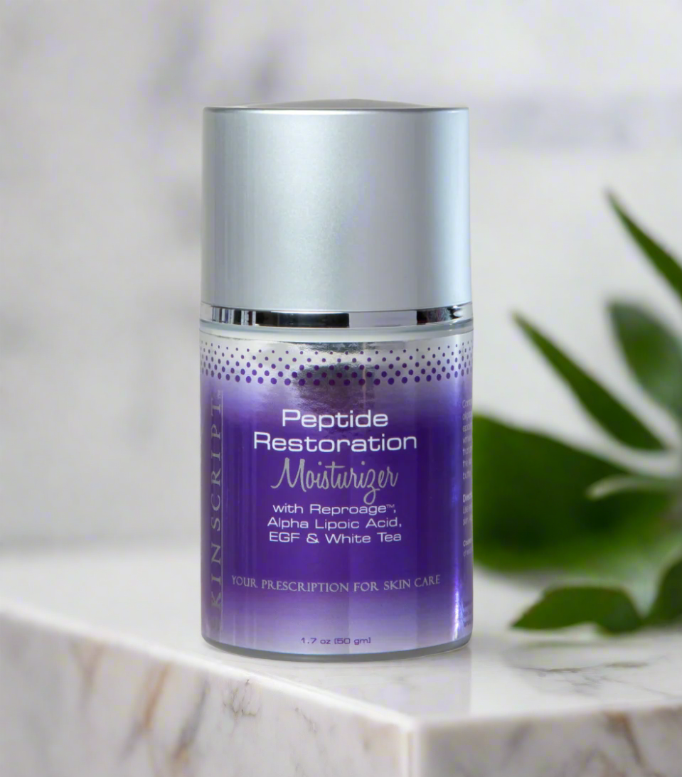 A pump bottle of SKINSCRIPTS Peptide Restoration Moisturizer with purple and white branding, placed on a marble surface with green leaf accents in the background.