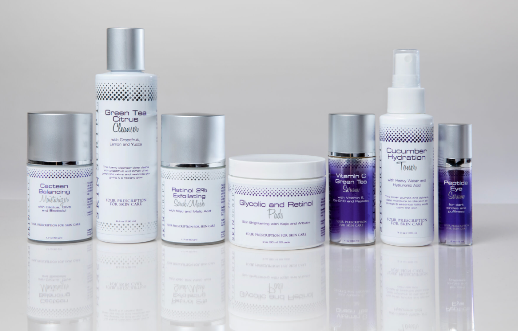A collection of skincare products displayed on a reflective surface, including cleansers, scrubs, toners, serums, and moisturizers.