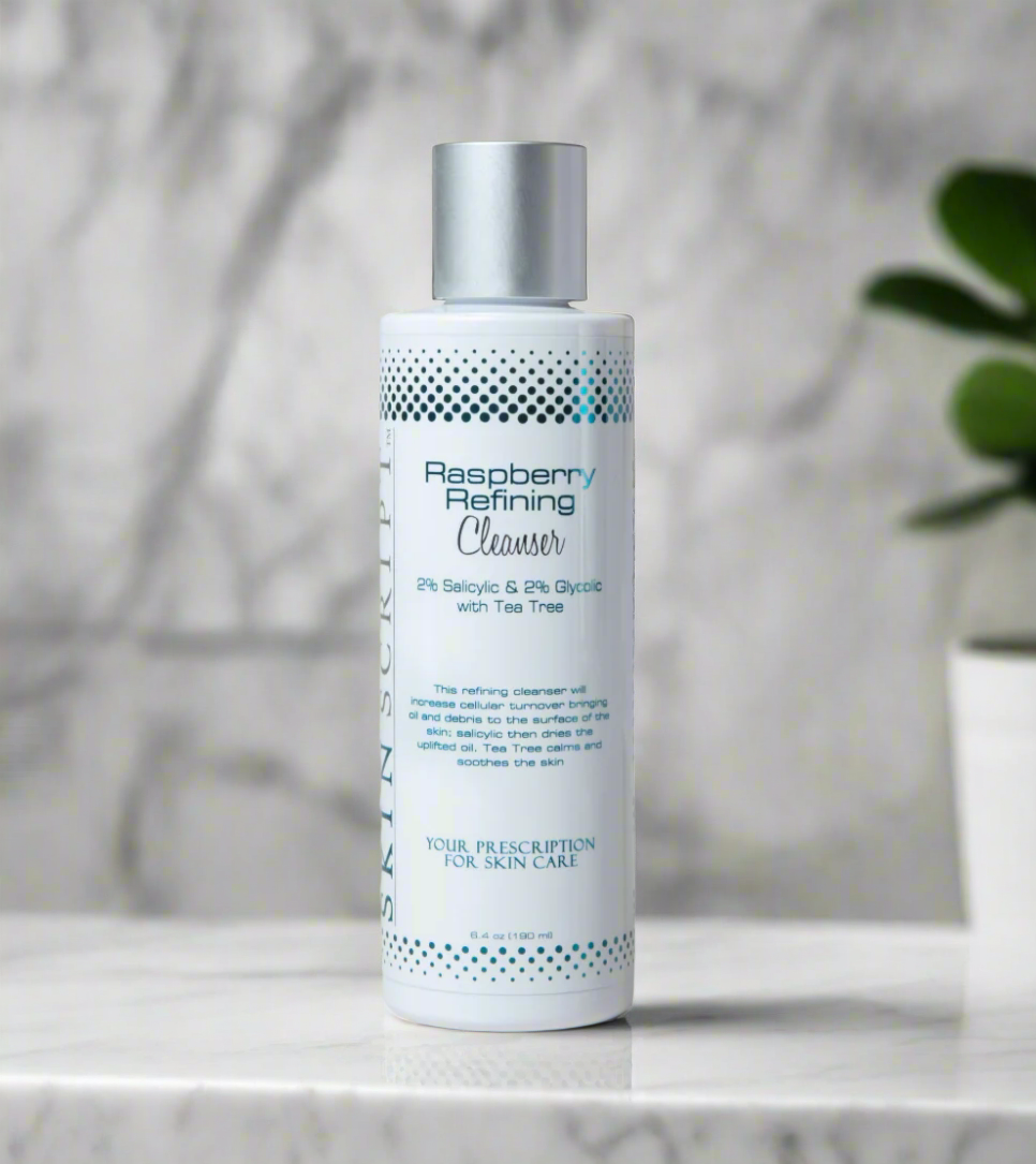 A bottle of SKINSCRIPTS Raspberry Refining Cleanser on a marble surface.