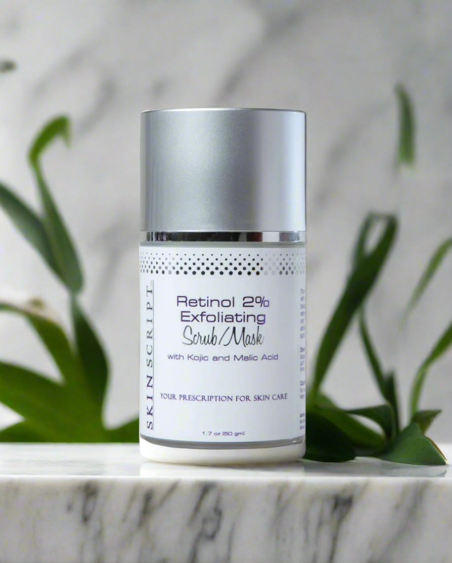 A jar of SKINSCRIPTS Retinol 2% Exfoliating Scrub / Mask placed on a marble surface with green leaves in the background.