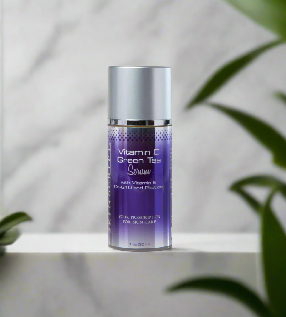 A bottle of SKINSCRIPTS Vitamin C Green Tea Serum placed on a marble surface with a plant in the background.
