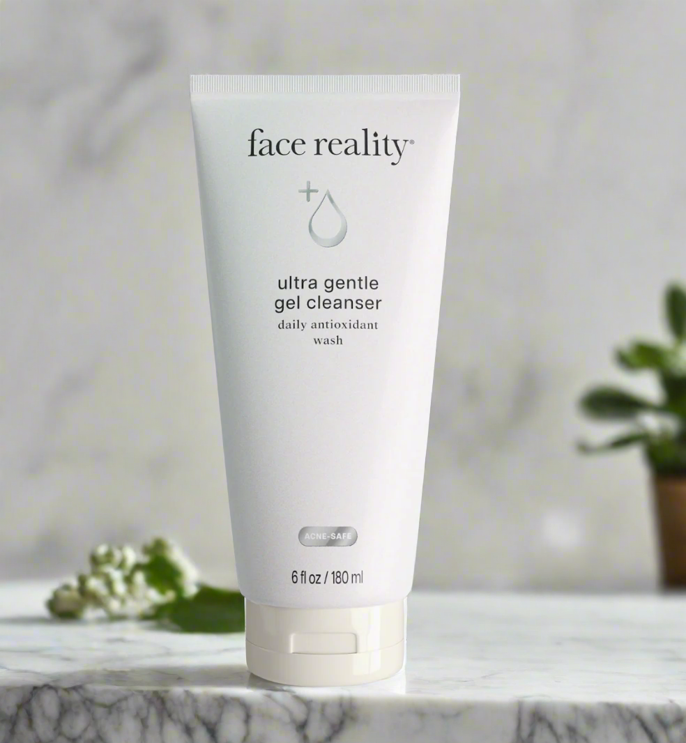 A tube of Face Reality Ultra Gentle Gel Cleanser placed on a surface with a plant in the background.