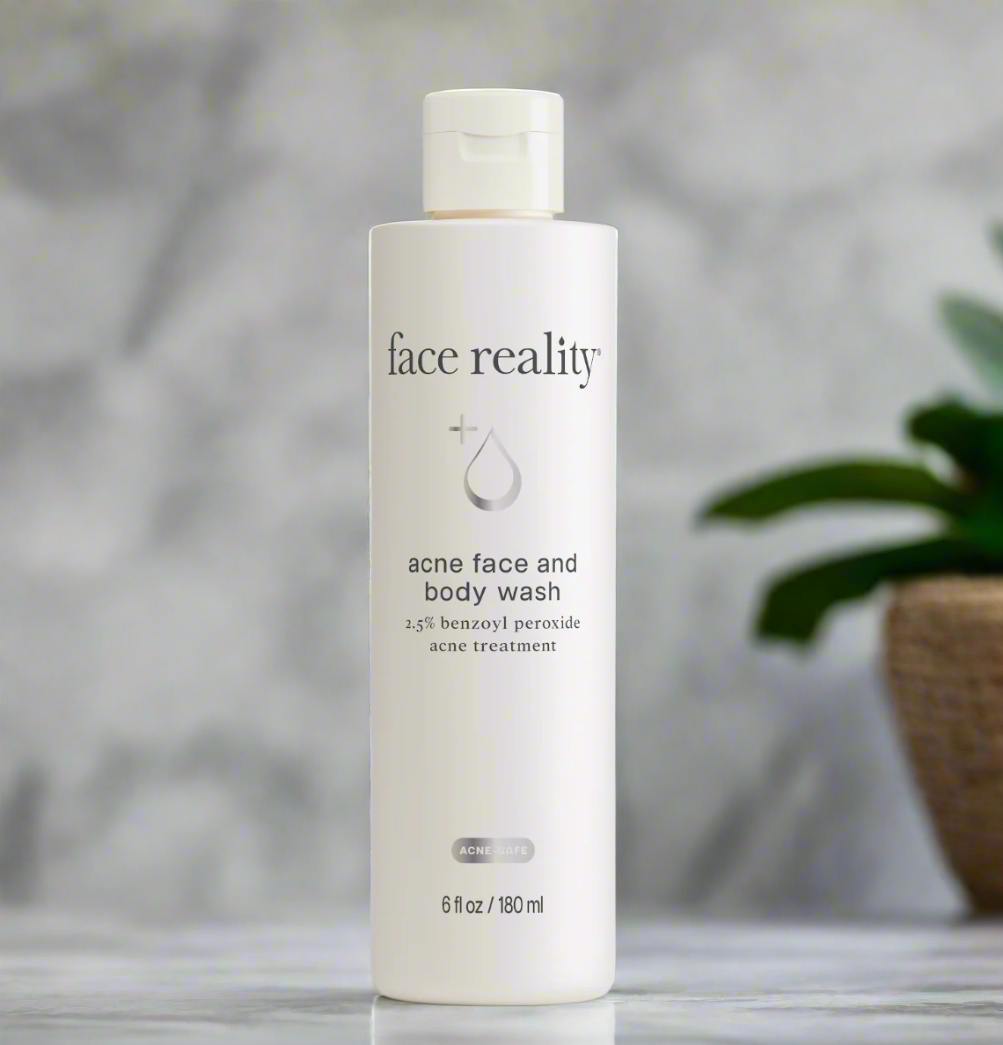 A bottle of Face Reality Acne Face and Body Wash with 2.5% benzoyl peroxide on a marble background.