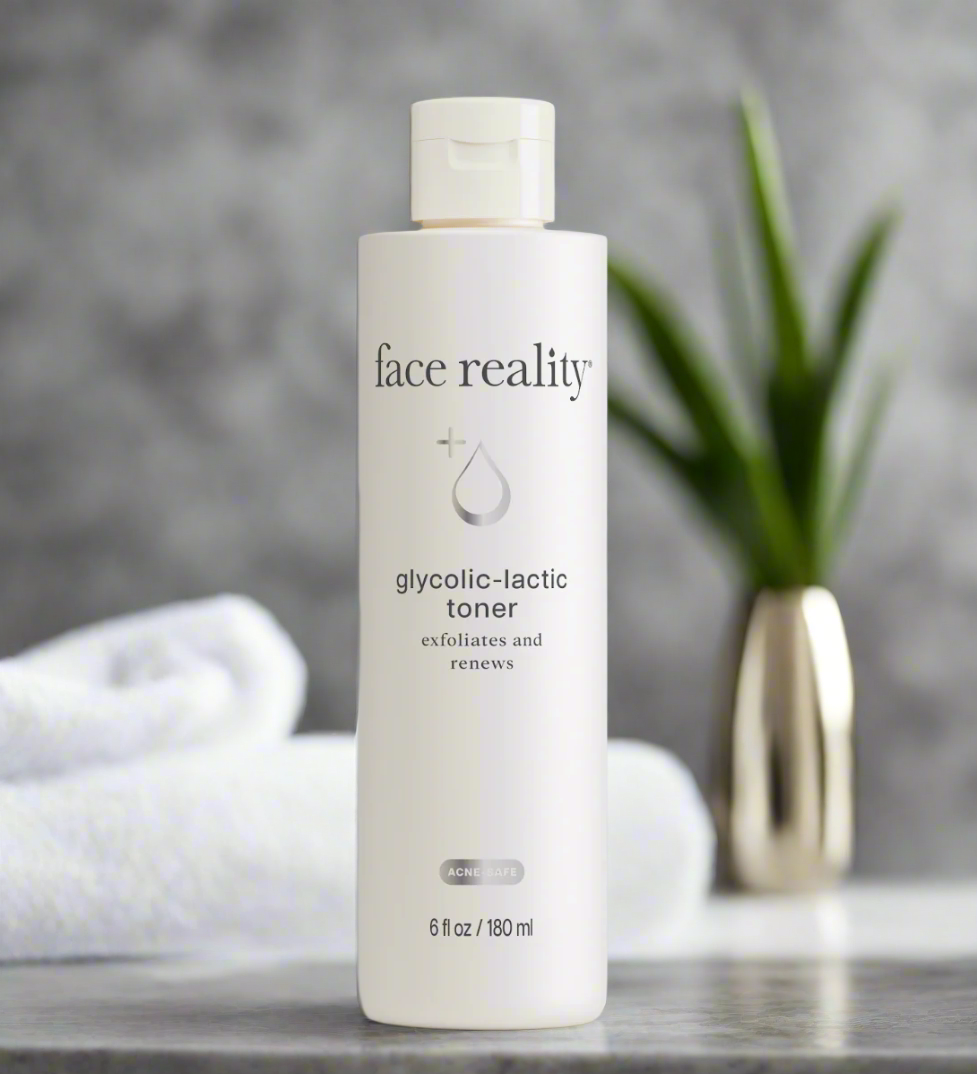 A bottle of Face Reality Glycolic-Lactic Toner placed on a surface with a towel and plant in the background.