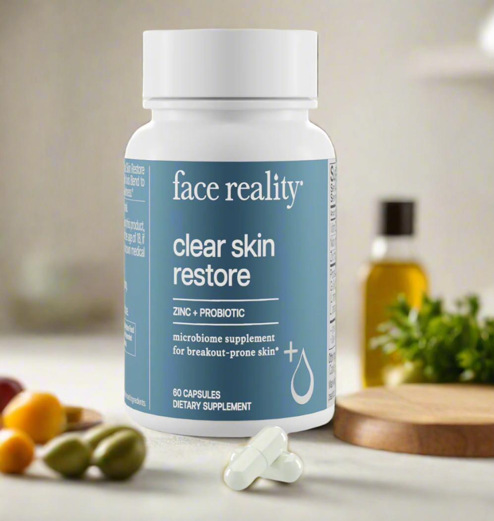 A bottle of Face Reality Clear Skin Restore supplements with 60 capsules, placed on a kitchen counter with various fruits and vegetables in the background.