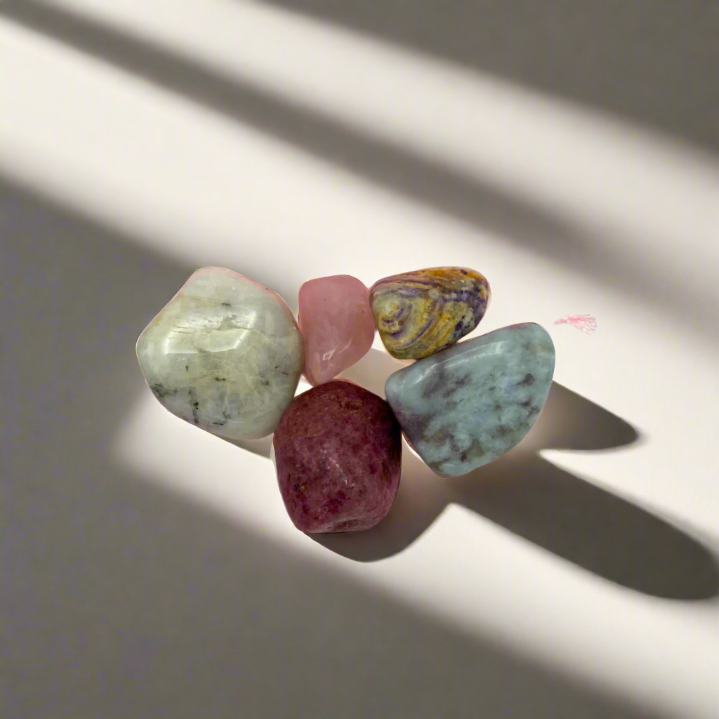 A collection of polished gemstones in various colors arranged on a light surface.