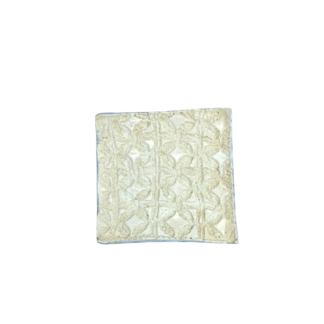 Top view of A beige square trinket dish with a floral pattern, on a white background.
