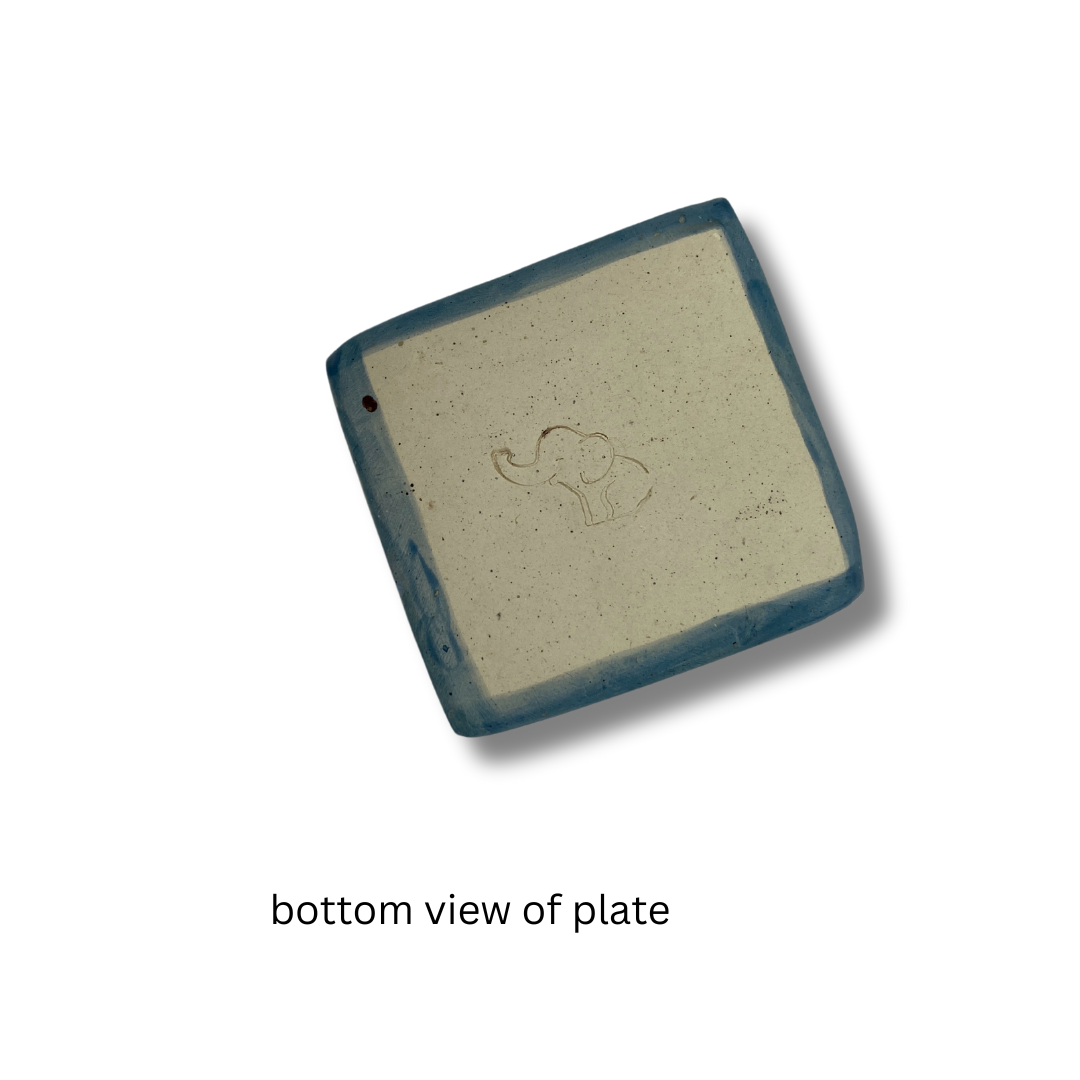 bottom view of TA beige square trinket dish with a floral pattern, on a white background.