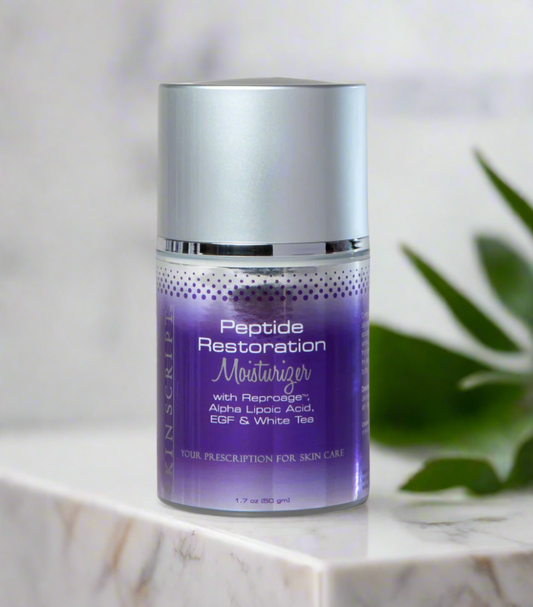 A pump bottle of SKINSCRIPTS Peptide Restoration Moisturizer with purple and white branding, placed on a marble surface with green leaf accents in the background.