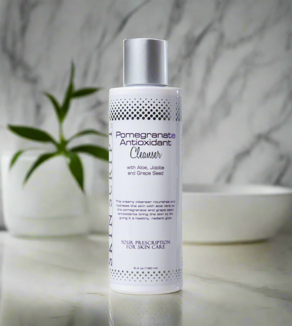 A  bottle of SKINSCRIPTS Pomegranate Antioxidant Cleanser on a marble surface with a plant in the background.