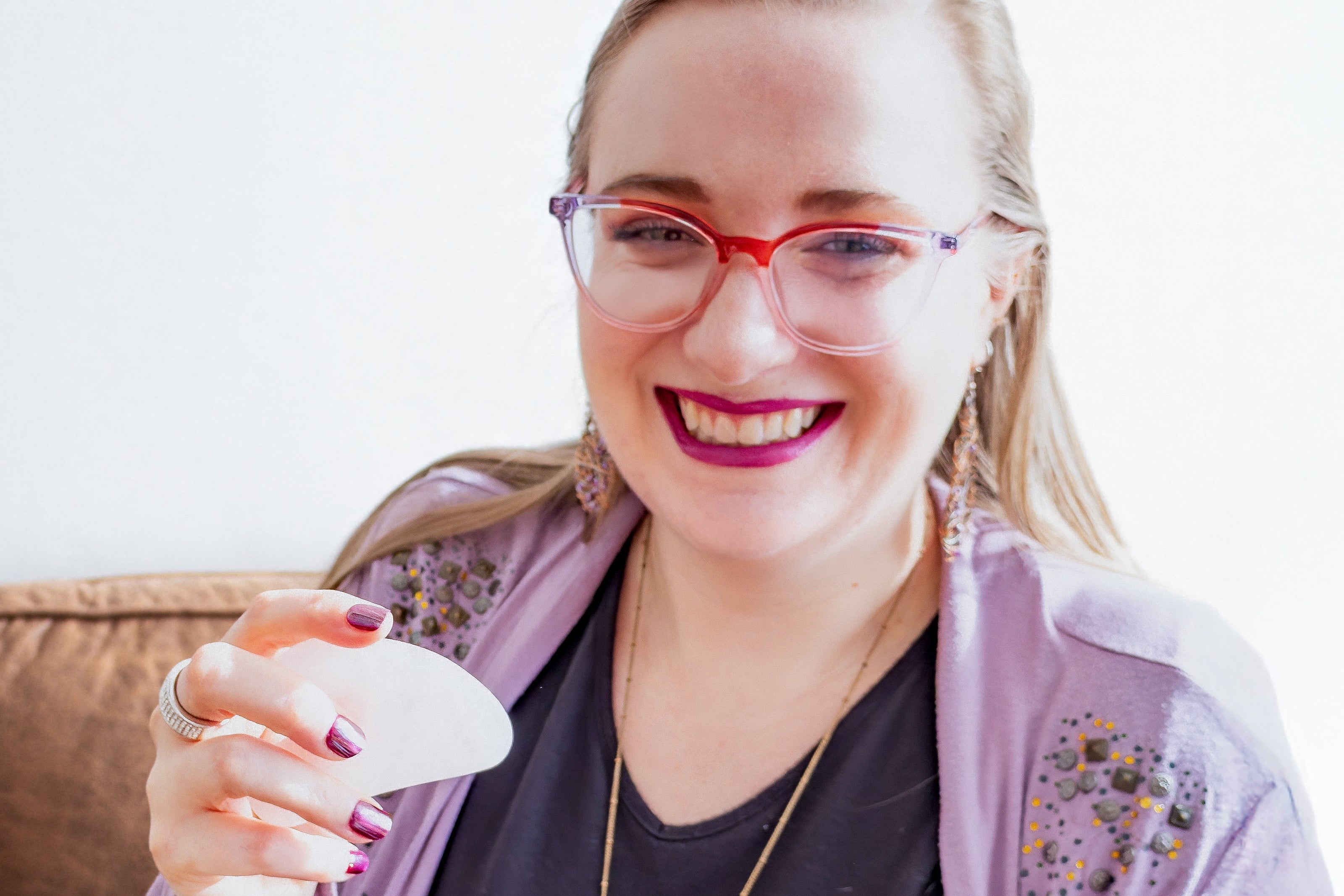 Woman holding gha stone,  smiling indoors.